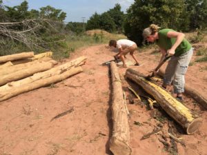 man woman skinning cutting logs for building their home