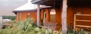 earthbag home front, porch swing, living off grid, solar lights, prickly pear cactus
